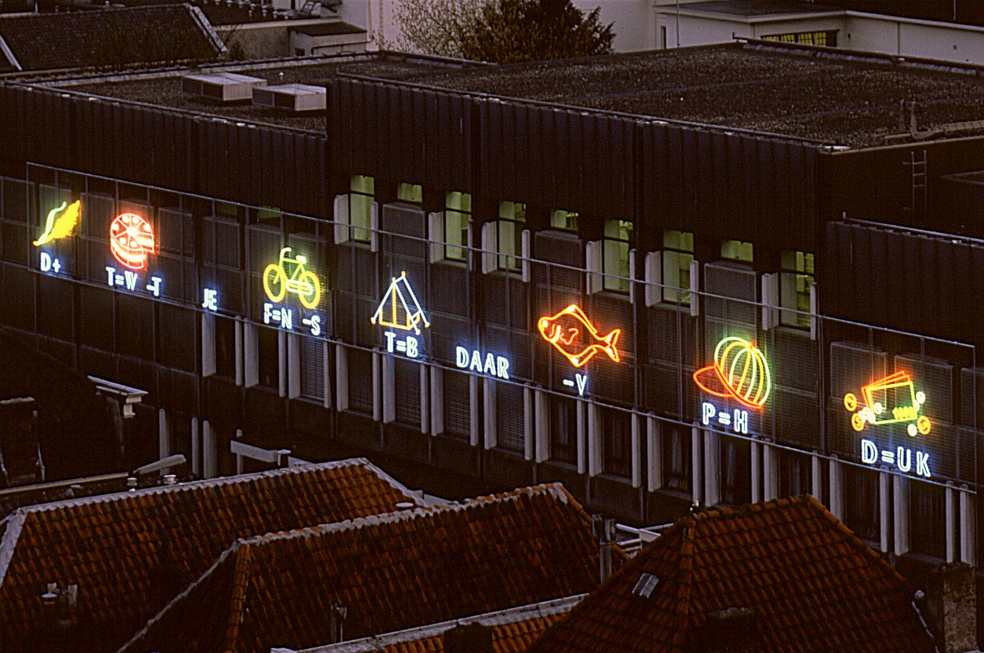 De lichten van de REBUS branden aan het Woudagebouw in de Lange Nieuwstraat. Het is avond op de foto. 