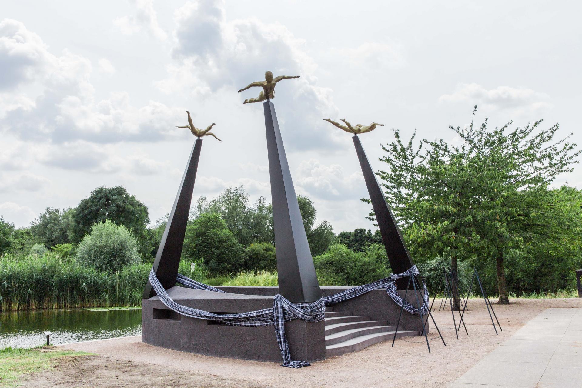monument van zwart beton met drie zuilen met een vliegende Afrikaanse figuur